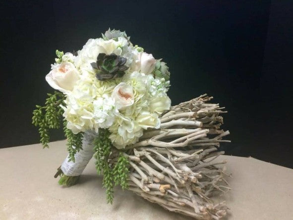 Bouquet with white flowers, greenery, and a branch on a dark background